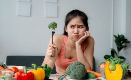 Researchers say the bitter ‘supertaster gene’ has long sparked interest in how taste perception influences health outcomes. Image: Adobe. An unimpressed woman holding up a piece of broccoli on a fork.